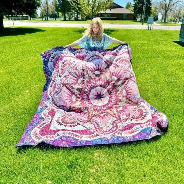 A woman laying on the grass with a blanket.