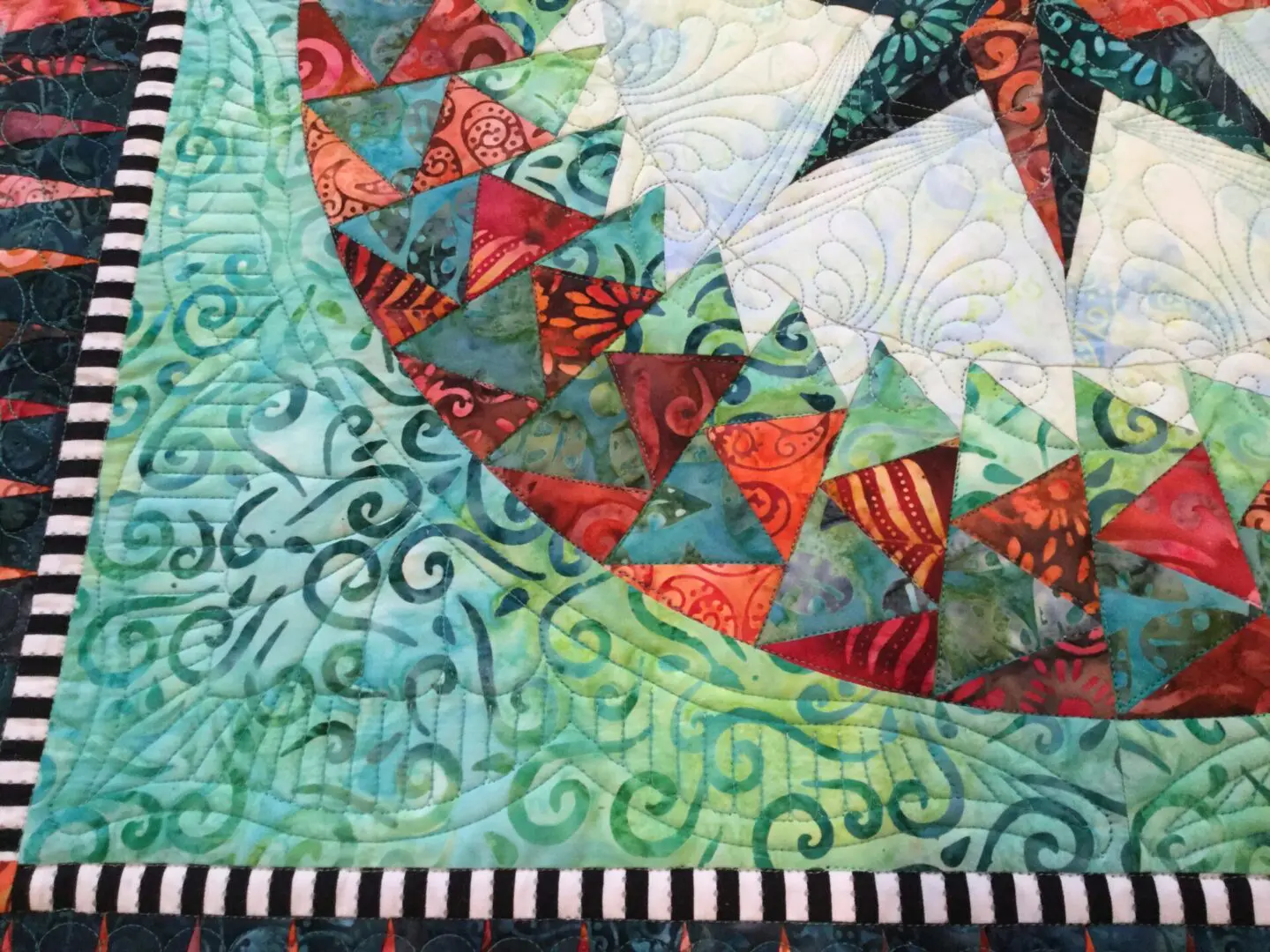 A close up of the quilt with swirls and shapes