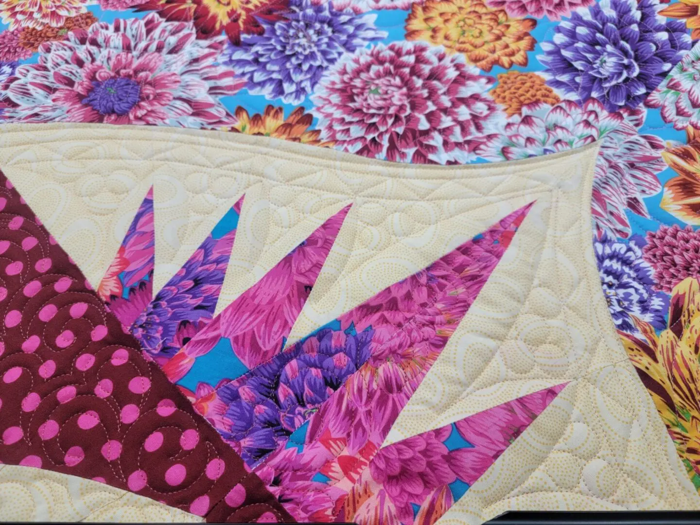 A close up of the quilt with purple flowers