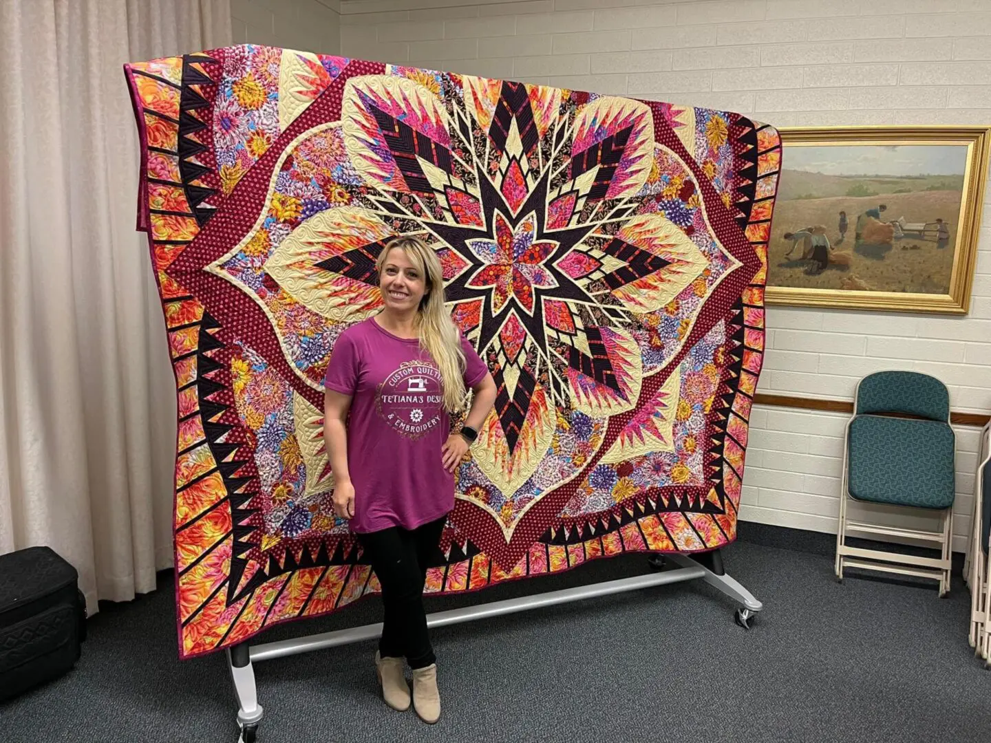 A woman standing next to a large quilt.