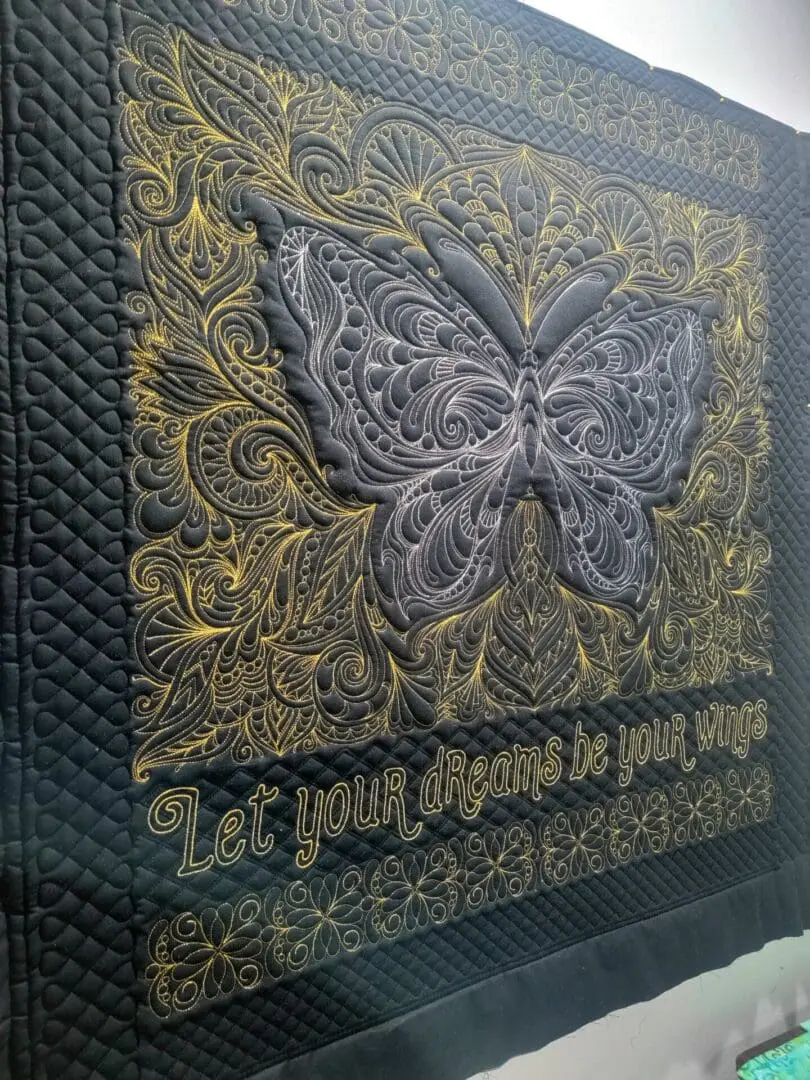 A black and gold butterfly quilt with the words " be your beautiful self ".