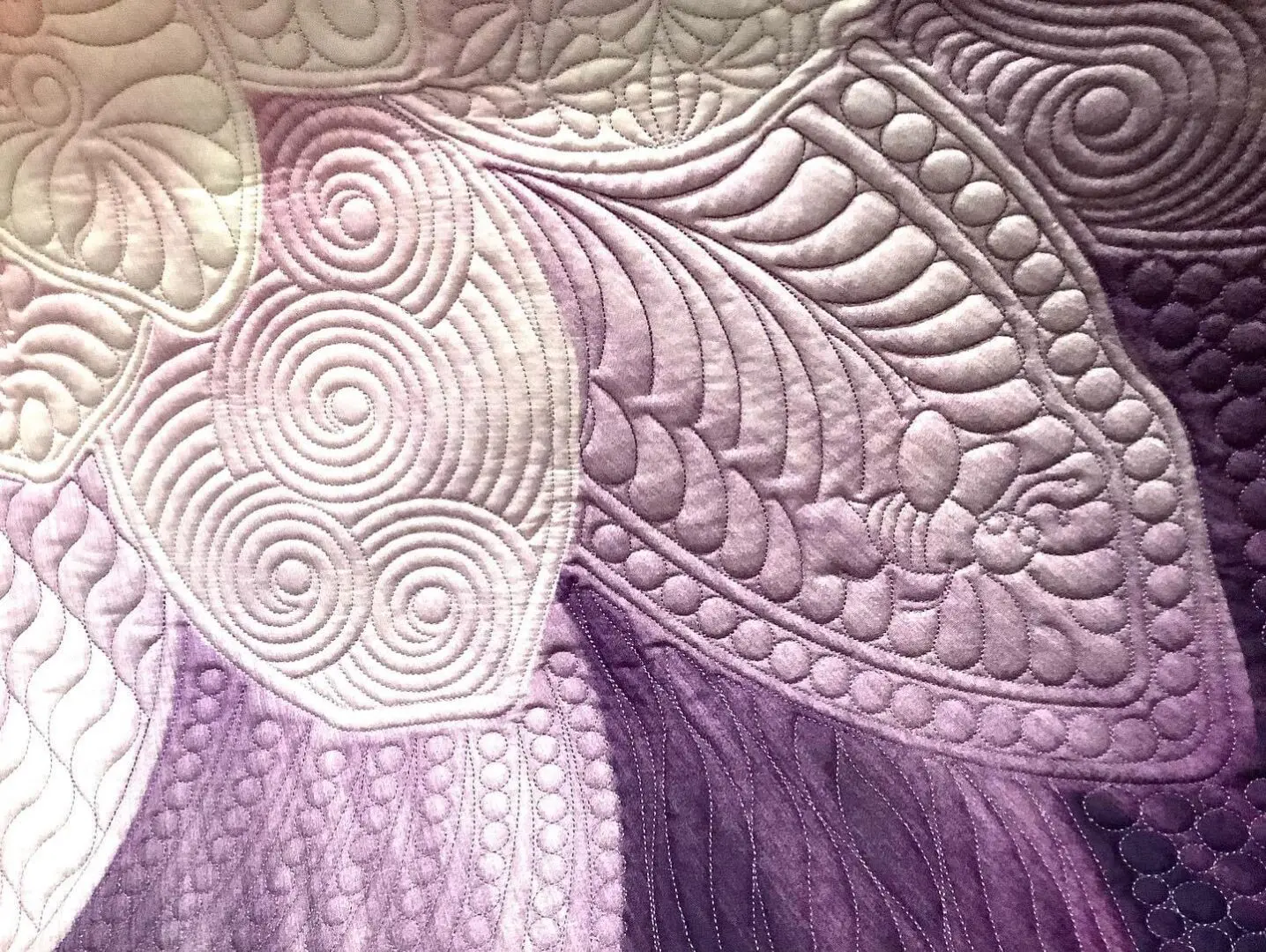 A close up of the fabric on a purple quilt