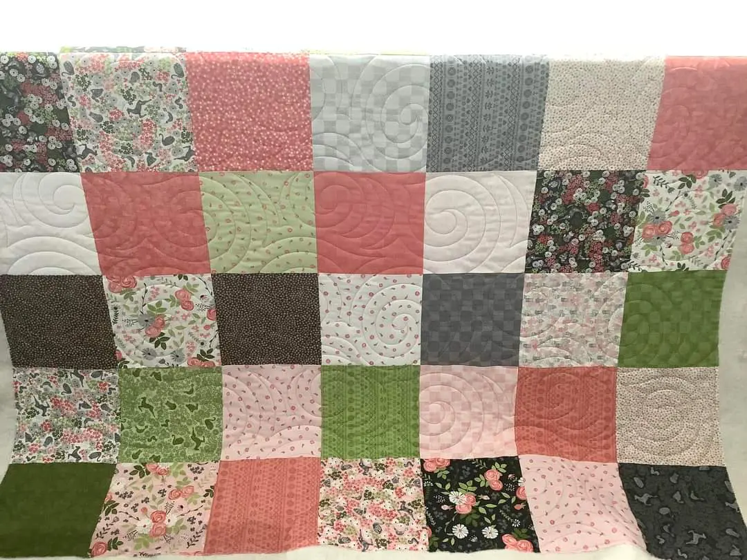 A quilt with different colored squares and flowers.