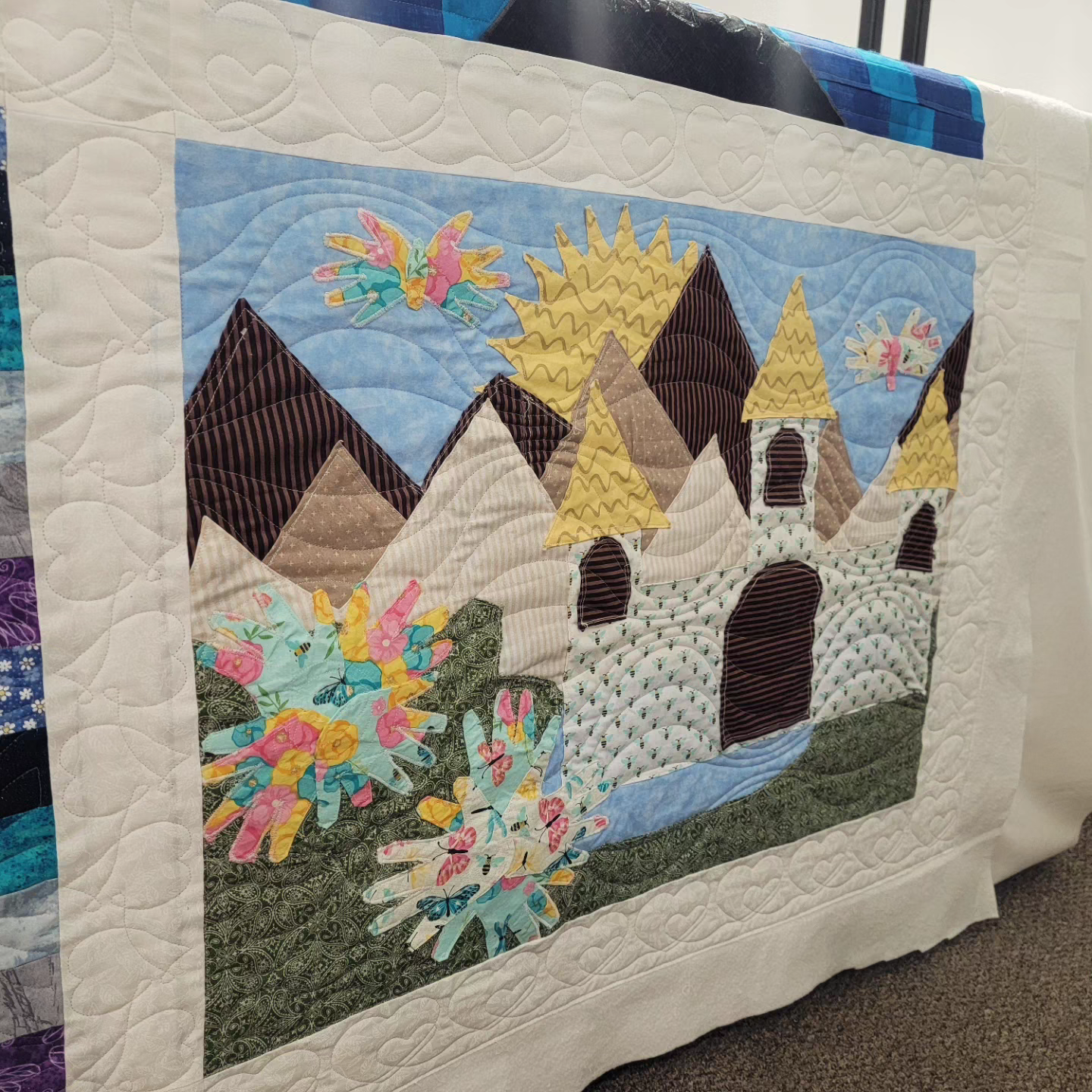 A quilt with a castle on it is sitting in the corner of a room.