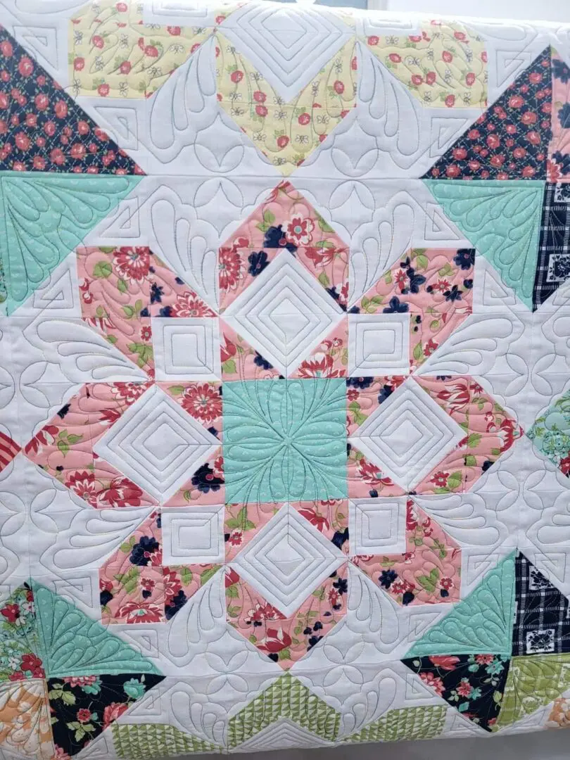 A quilt with different colored squares and white designs.