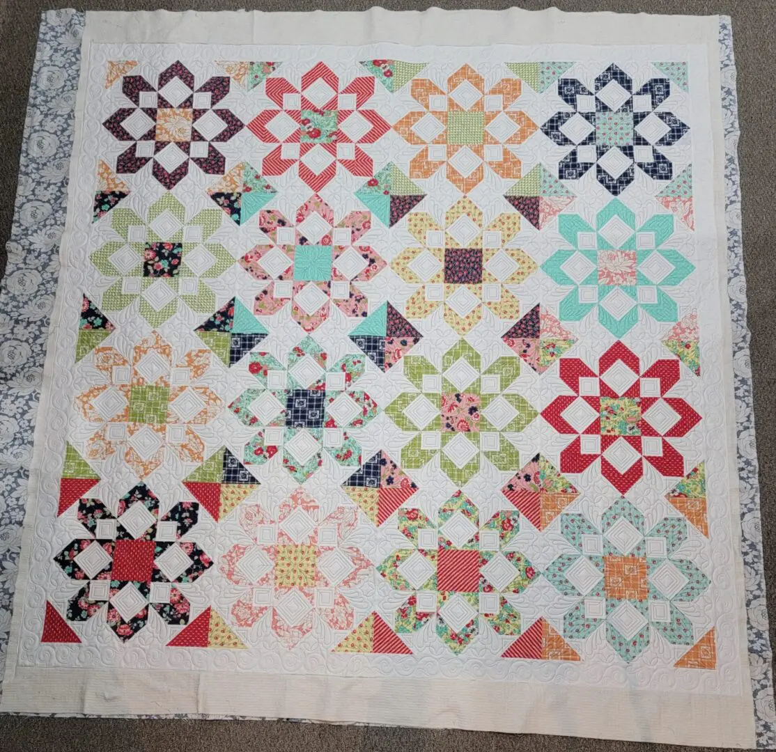 A quilt with different colored flowers on it.