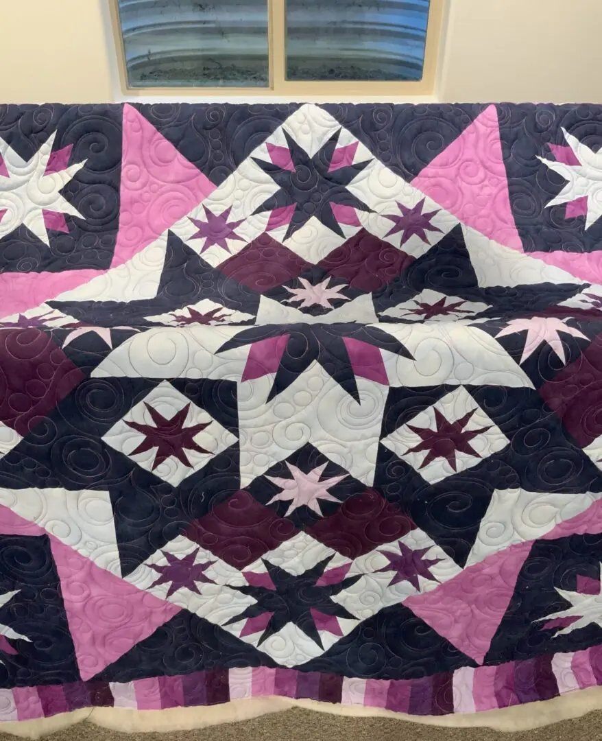 A quilt with purple and white stars on it.