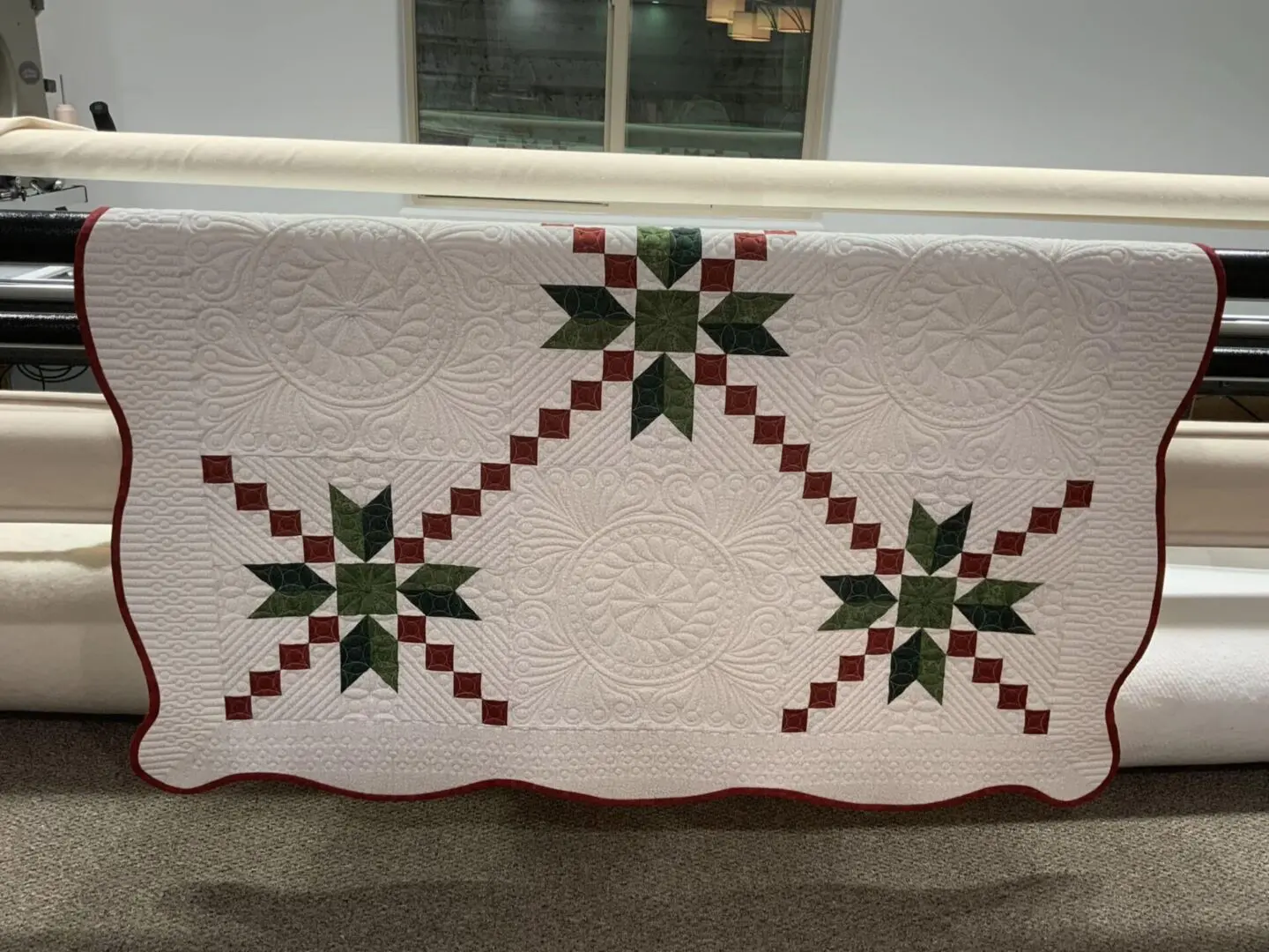 A white quilt with green and red stars on it.