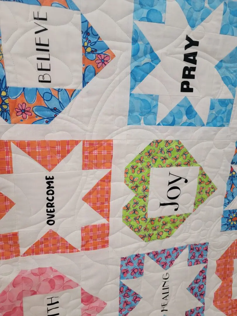 A quilt with different colored squares and words on it.